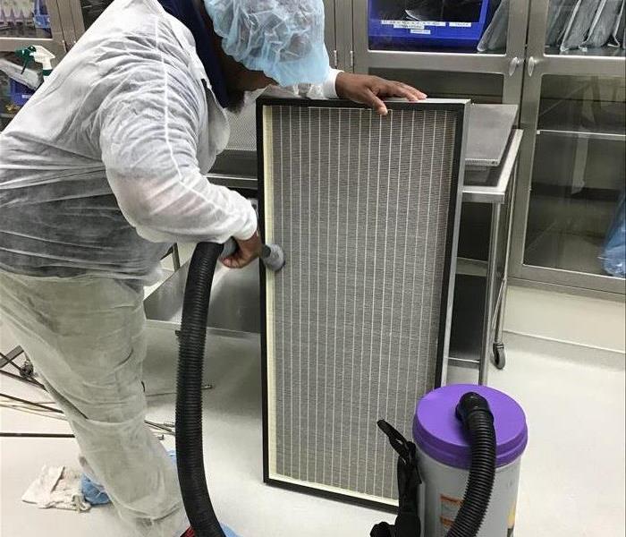 SERVPRO of Lake Charles employee using a hepa filtered vacuum on a commercial grade air filter to aid in duct cleaning.